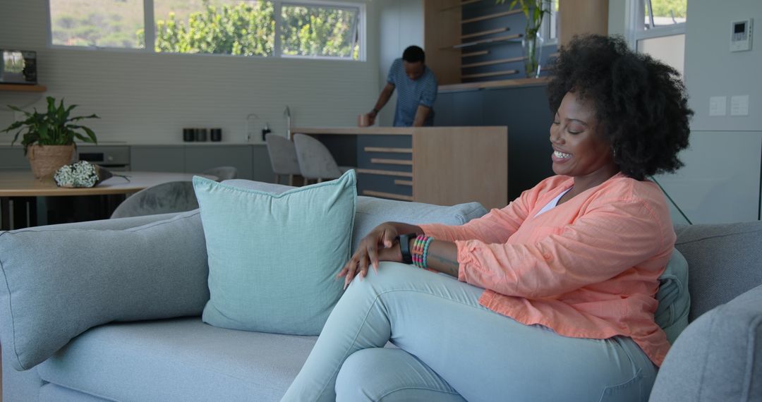 Smiling Woman on Sofa with Partner in Kitchen at Modern Home