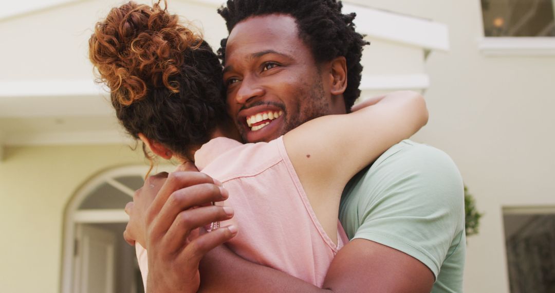 Happy Biracial Couple Embracing in Front of New Home
