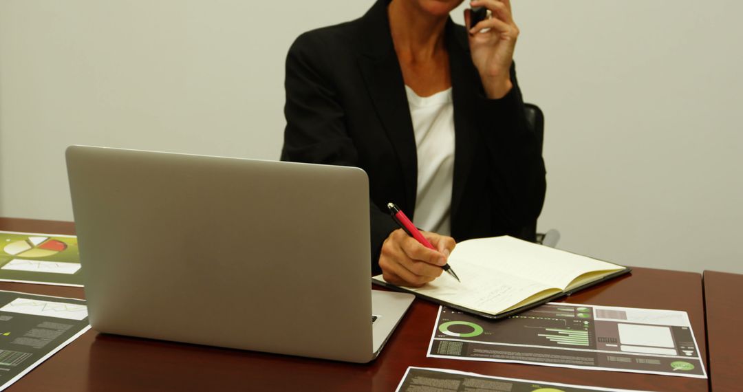 Businesswoman multitasking in office with laptop, charts, and smartphone - Free Images, Stock Photos and Pictures on Pikwizard.com