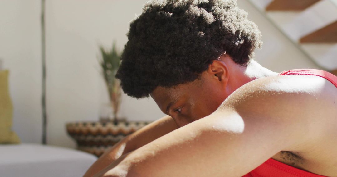 Man resting head on forearms, sunlit contemplative moment in minimalist living room