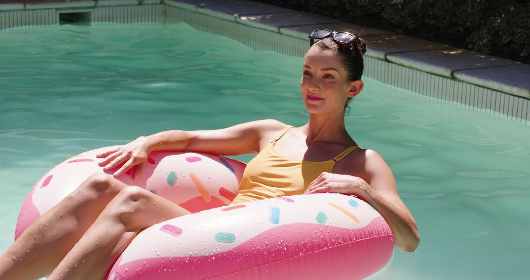 Middle-Aged Woman Relaxing on Donut Float in Backyard Pool on Sunny Day
