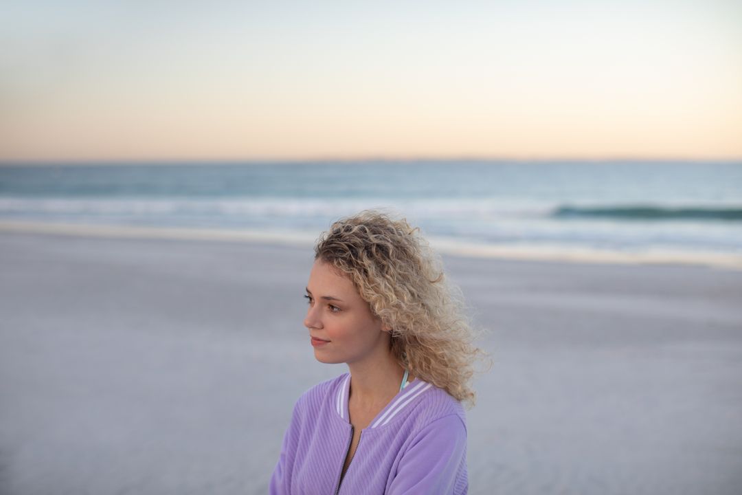 Thoughtful Woman with Curly Hair Standing on Beach at Sunset - Free Images, Stock Photos and Pictures on Pikwizard.com