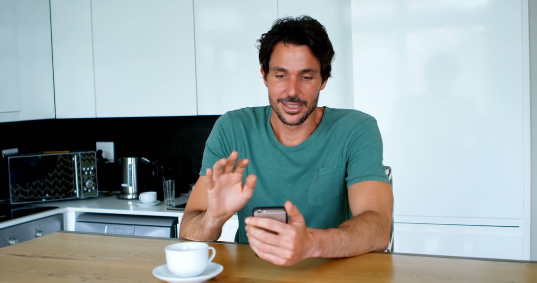 Man Drinking Coffee at Kitchen Table Using Smartphone - Free Images, Stock Photos and Pictures on Pikwizard.com