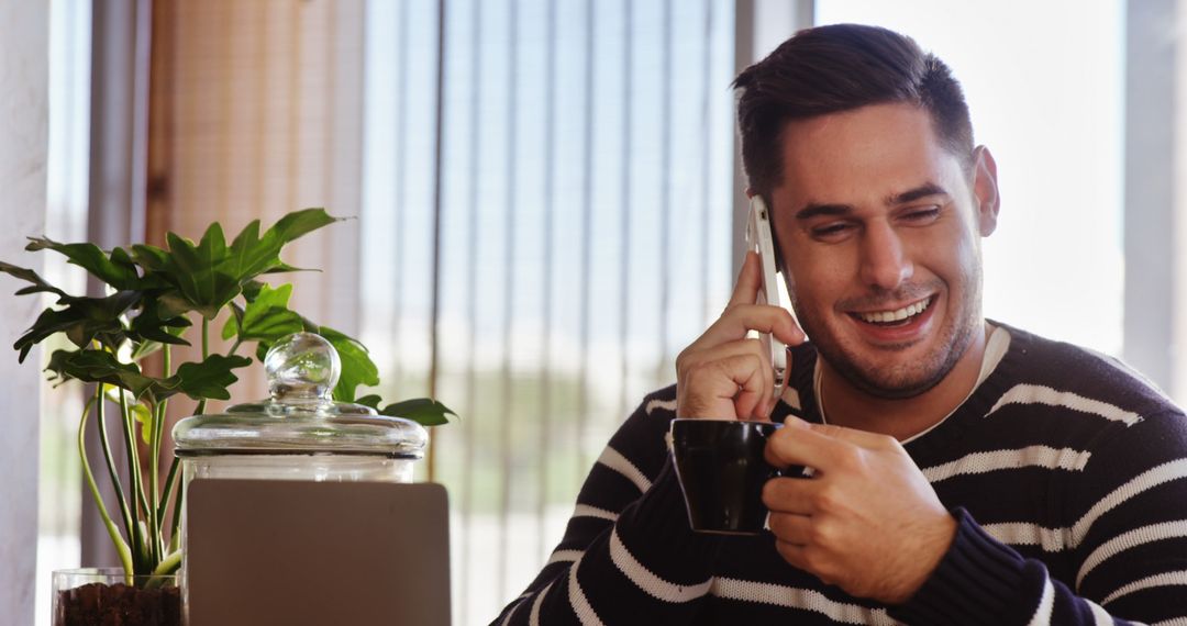 Smiling Man in Cafe Talking on Smartphone with Coffee