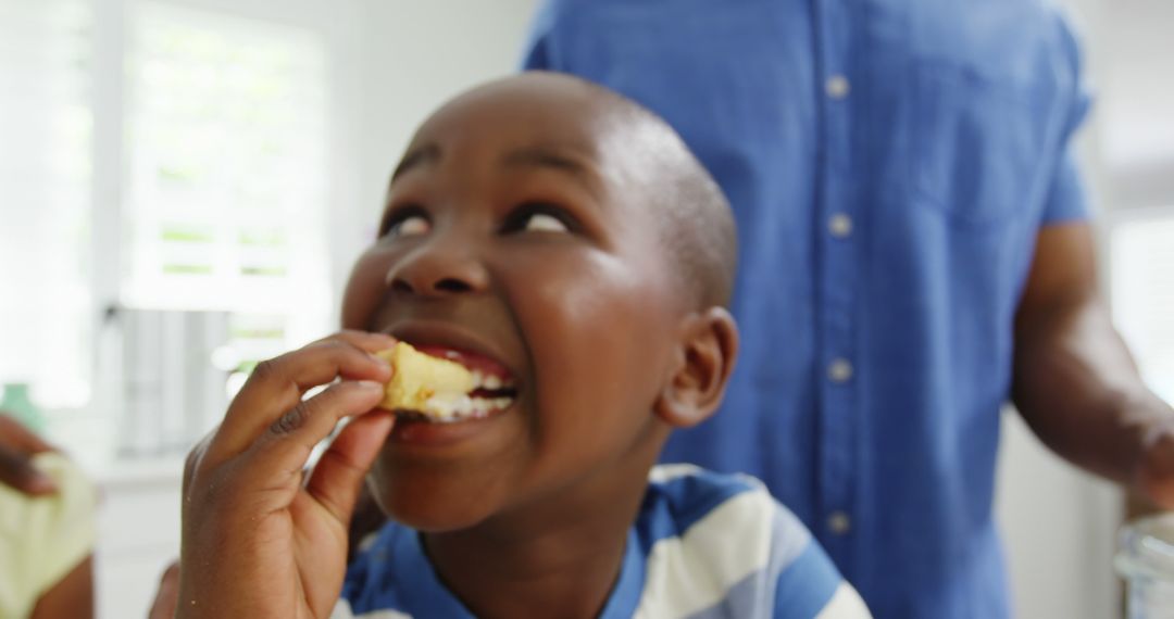 Smiling Boy Eating A Delicious Pastry In Kitchen - Free Images, Stock Photos and Pictures on Pikwizard.com