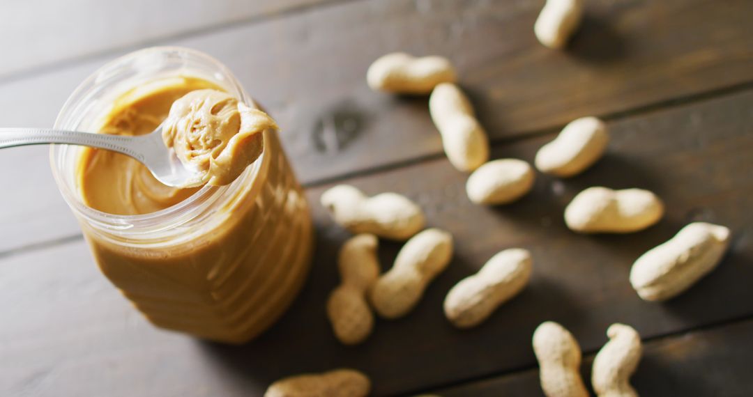 Creamy Peanut Butter with Raw Peanuts on Wooden Table