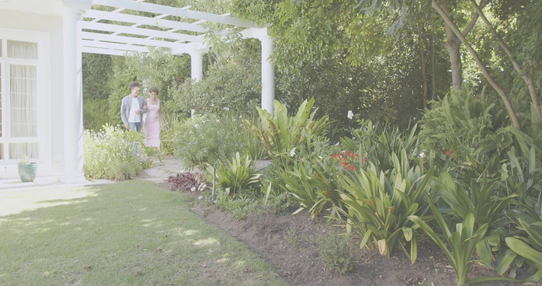 Couple Walking Through Lush Garden Pergola Along Sunlit Path With Romantic Atmosphere
