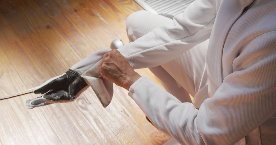 Fencer Preparing Glove for Competition on Wooden Floor - Free Images, Stock Photos and Pictures on Pikwizard.com