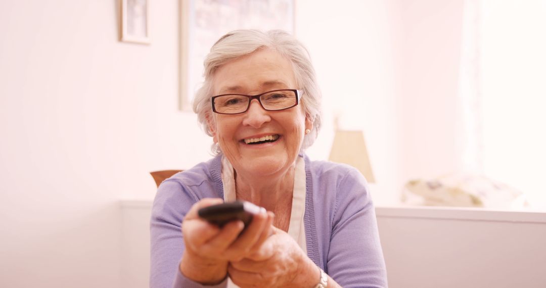 Senior Woman Smiling and Holding Remote Control - Free Images, Stock Photos and Pictures on Pikwizard.com