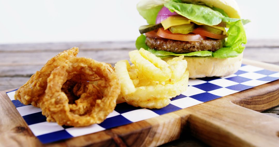 Gourmet Burger with Onion Rings and Crinkle-Cut French Fries on Wooden Board - Free Images, Stock Photos and Pictures on Pikwizard.com