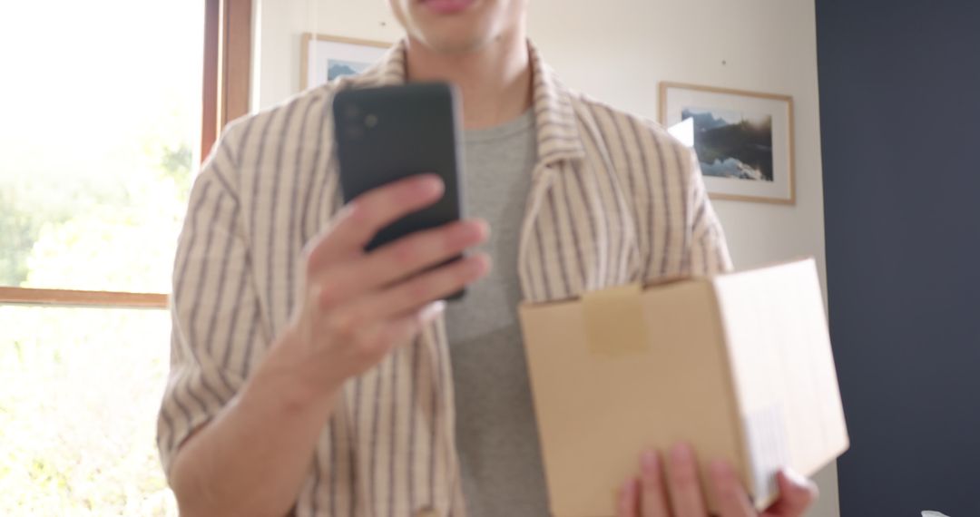 Man Checking Smartphone Holding Cardboard Delivery Package