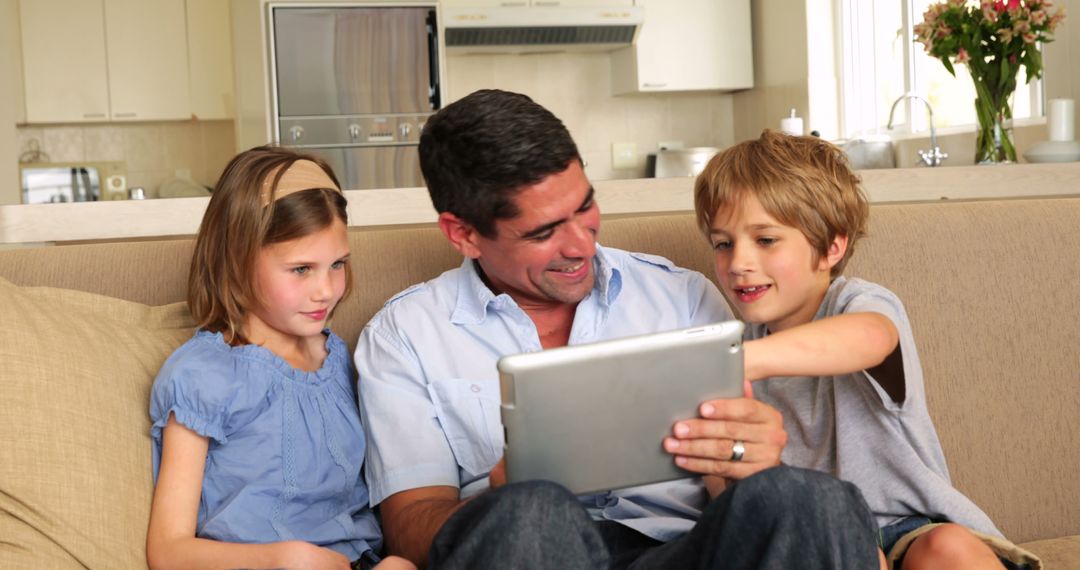 Father with children using digital tablet on sofa in modern home - Free Images, Stock Photos and Pictures on Pikwizard.com