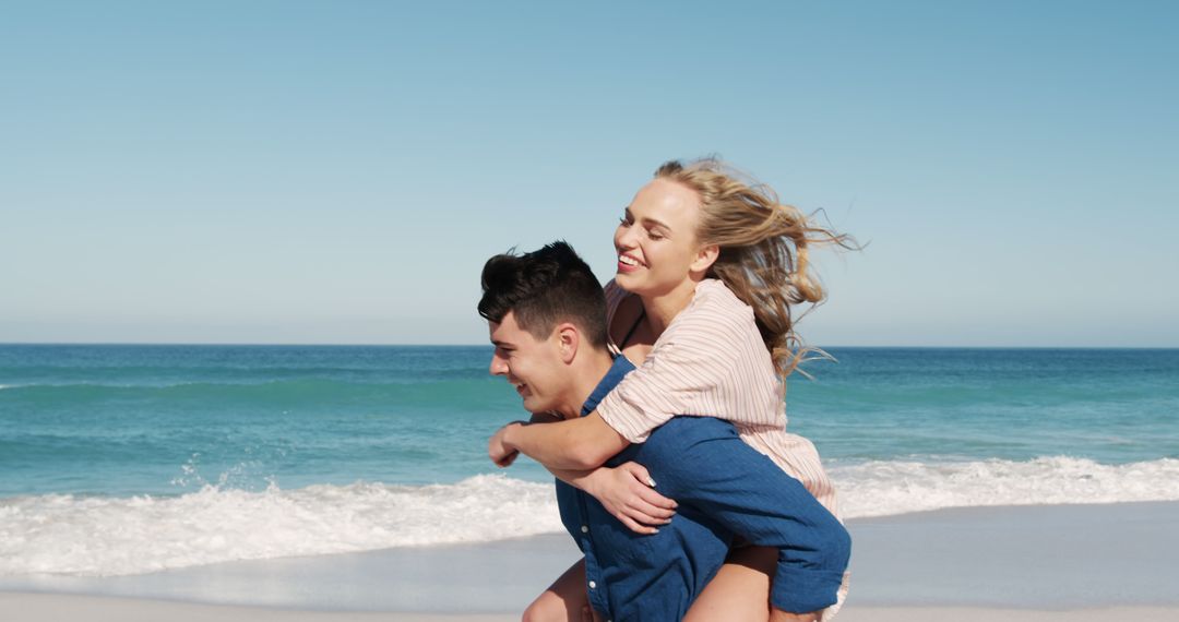 Happy Couple Enjoying Piggyback Ride on Beach on Sunny Day - Free Images, Stock Photos and Pictures on Pikwizard.com