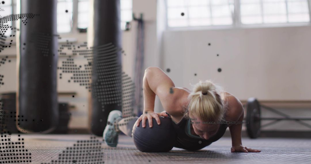 Performing single-arm stability pushup on medicine ball in gym studio for core strength