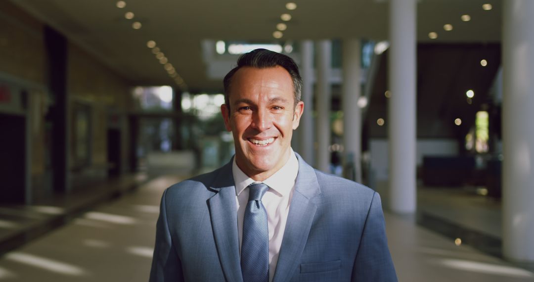 Confident Businessman Smiling Inside Modern Office Building - Free Images, Stock Photos and Pictures on Pikwizard.com