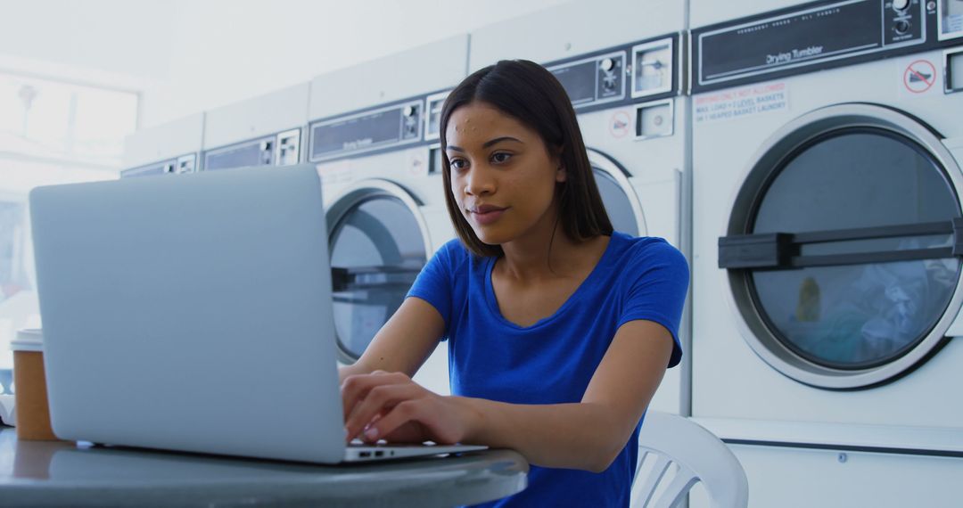 Concentrated Woman Using Laptop in Laundromat - Free Images, Stock Photos and Pictures on Pikwizard.com