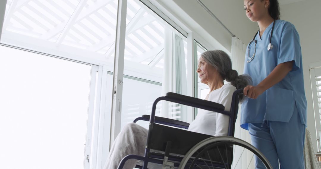 Nurse Assisting Elderly Woman in Wheelchair by Window - Free Images, Stock Photos and Pictures on Pikwizard.com