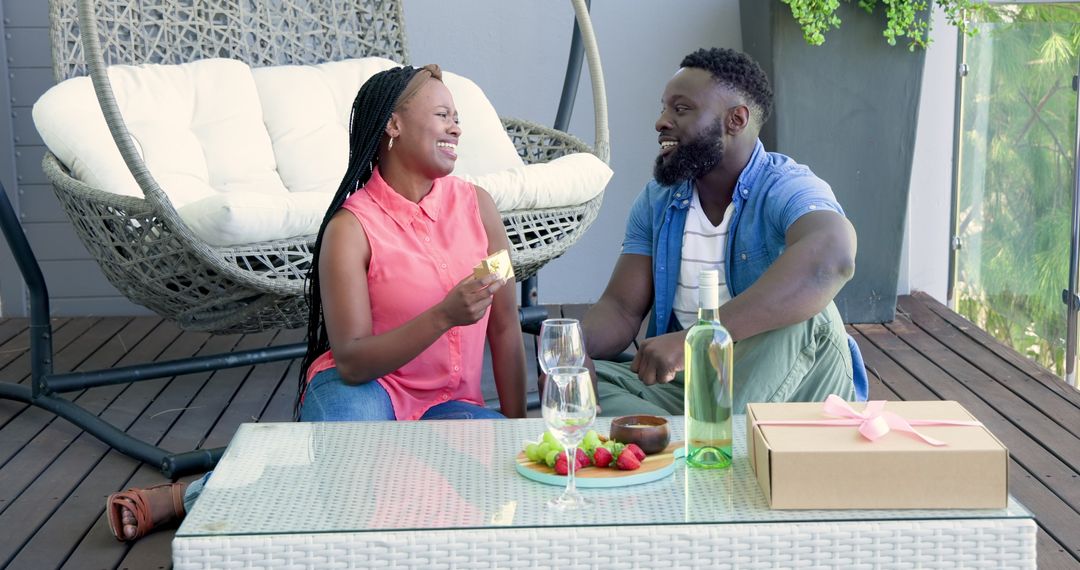 Couple Enjoying Picnic Date with Wine and Gift on Modern Patio