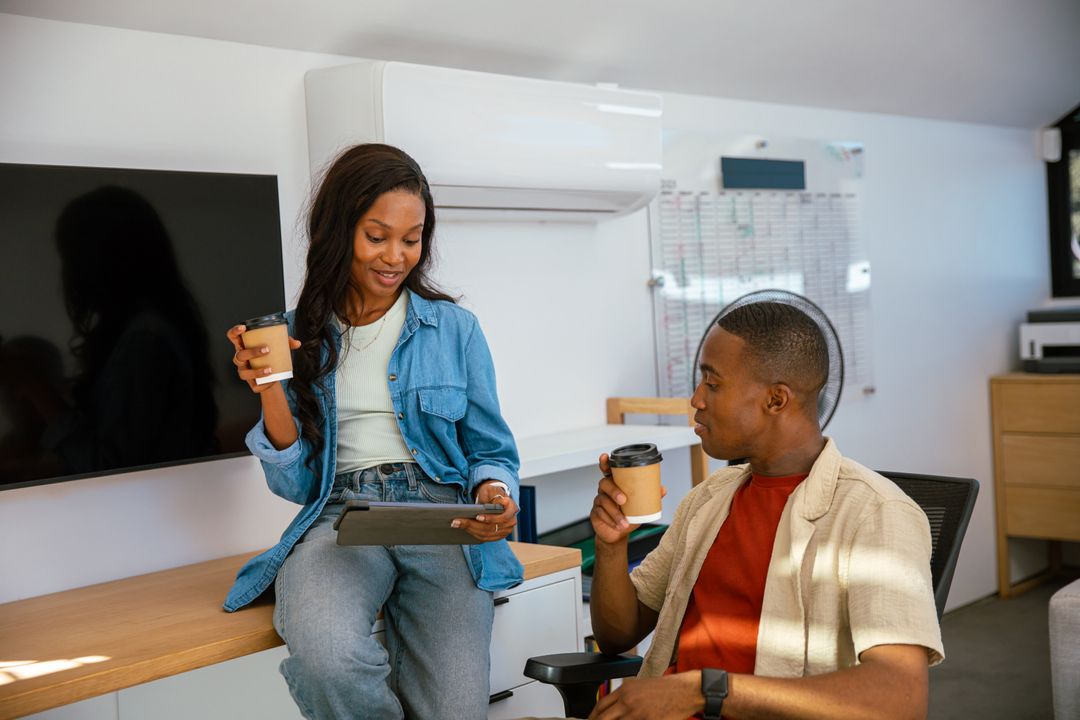 Colleagues Discussing with Coffee and Tablet in Modern Office