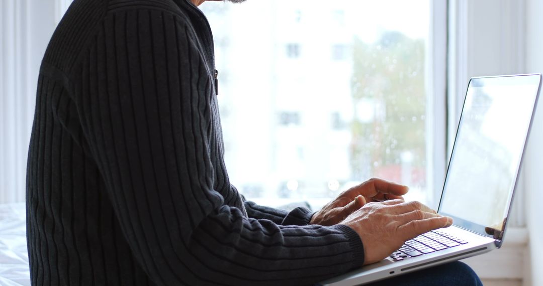 Man Working Remotely on Laptop by Window - Free Images, Stock Photos and Pictures on Pikwizard.com