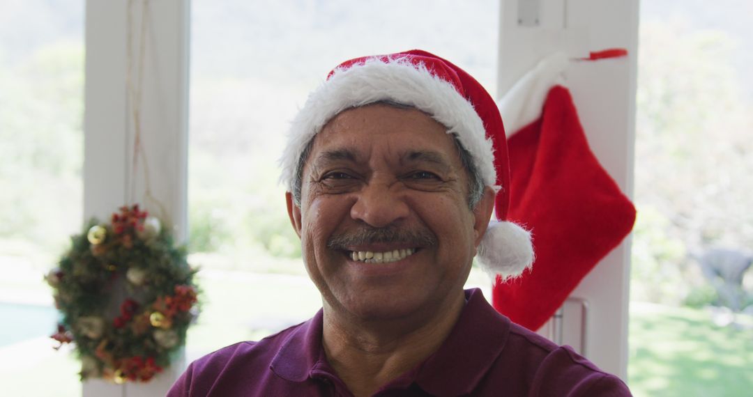 Smiling Senior Man Wearing Santa Hat During Holiday Season - Free Images, Stock Photos and Pictures on Pikwizard.com