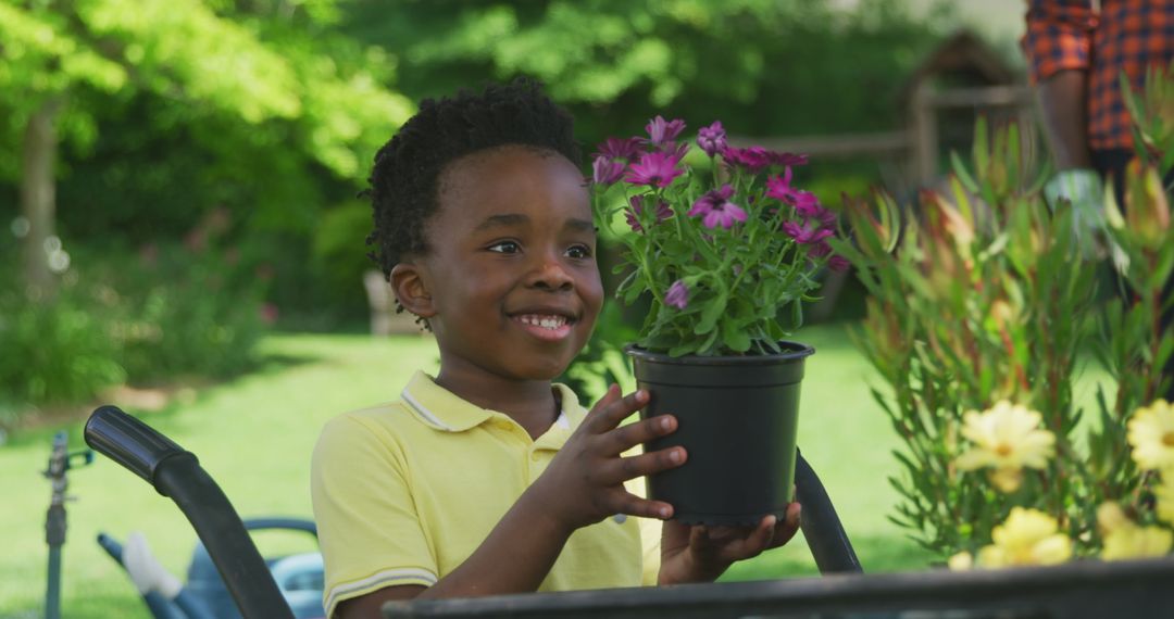 Joyful Boy Holding Potted Plant in Sunlit Garden
