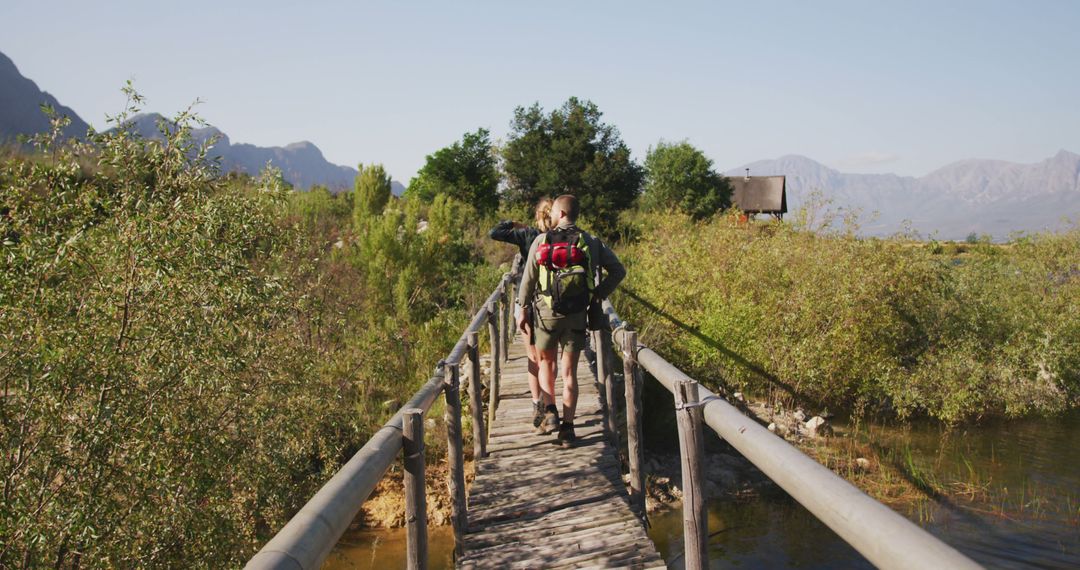 Hikers Crossing Wooden Bridge in Scenic Mountain Landscape - Free Images, Stock Photos and Pictures on Pikwizard.com