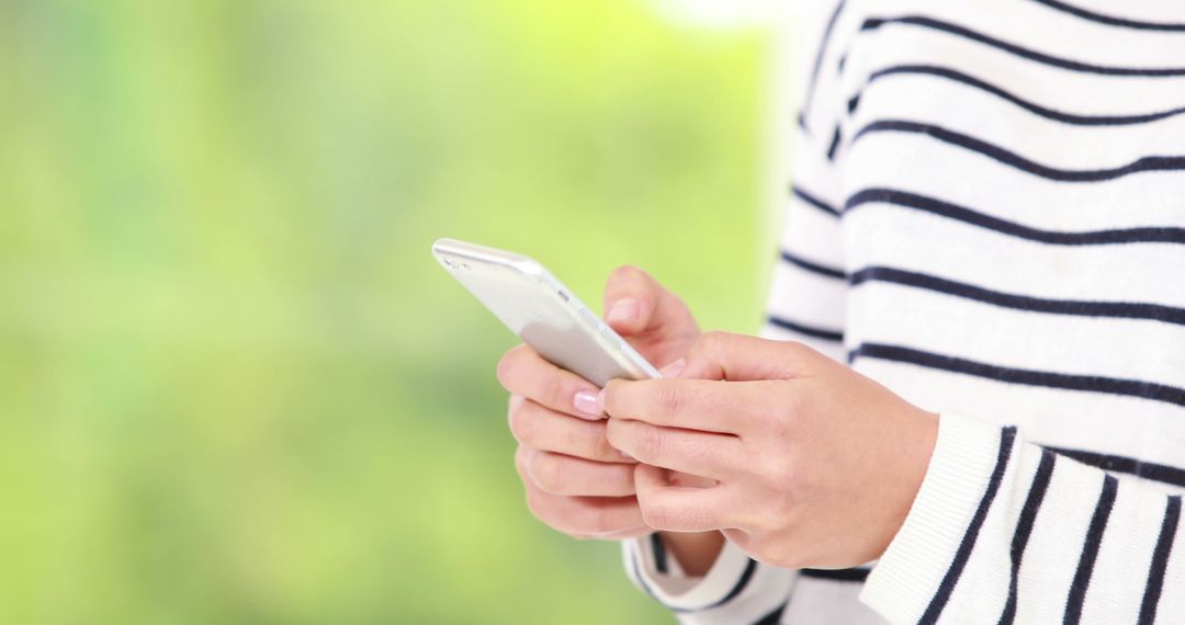 Person Texting on Smartphone in Striped Shirt with Green Background - Free Images, Stock Photos and Pictures on Pikwizard.com