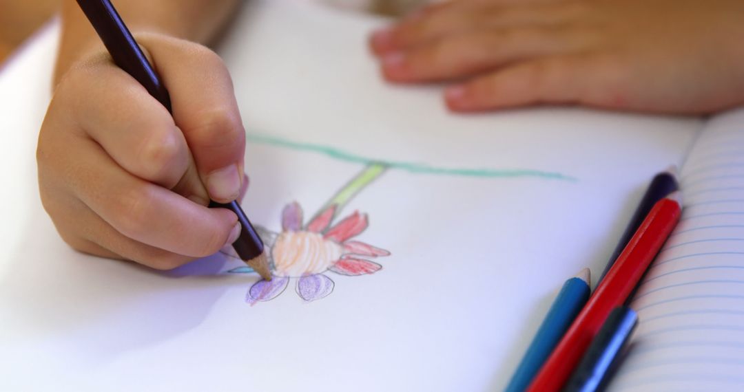 A child is focused on drawing a colorful flower with crayons, with copy space - Free Images, Stock Photos and Pictures on Pikwizard.com