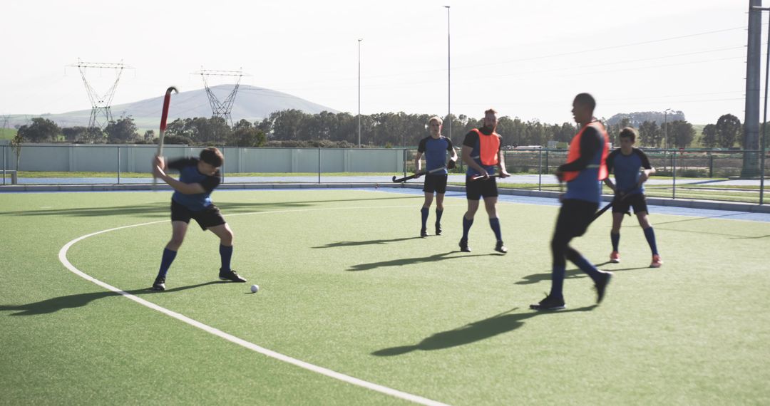 Diverse Field Hockey Team Practicing Striking Techniques on Turf