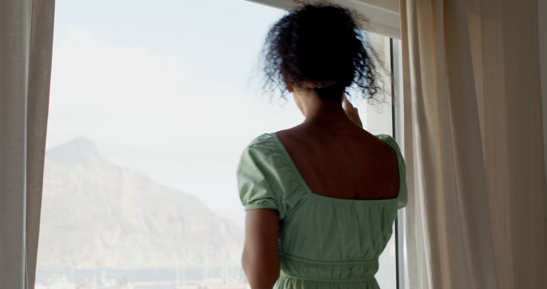 Woman Enjoying Scenic Coastal View from Hotel Window