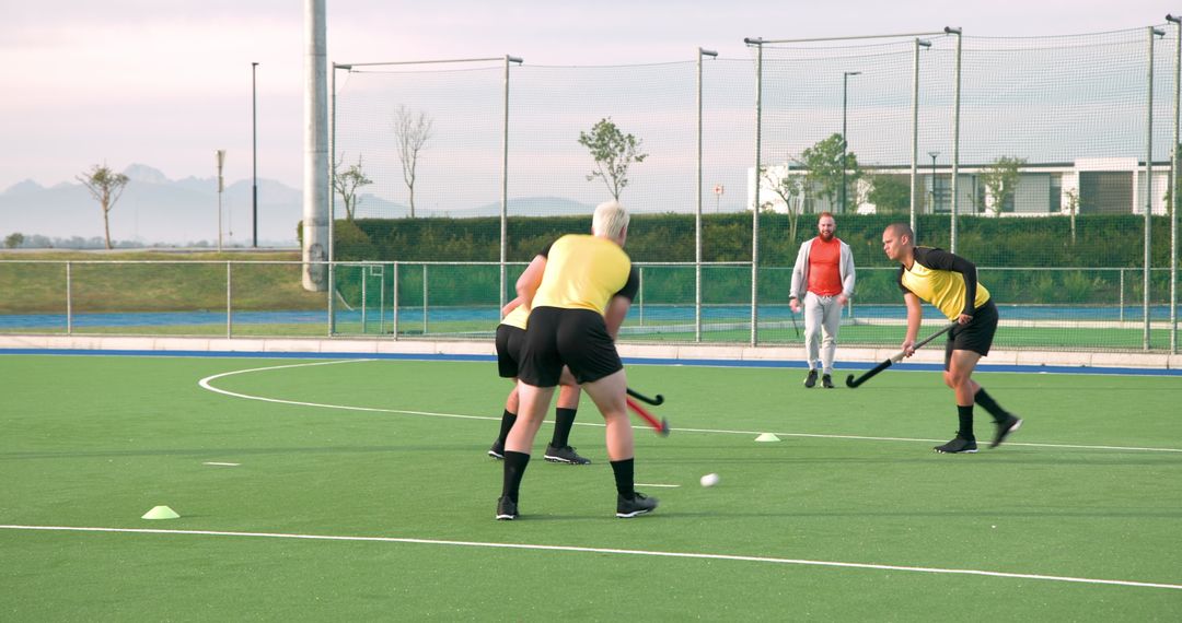 Field Hockey Players Practicing on Turf with Coach Overseeing