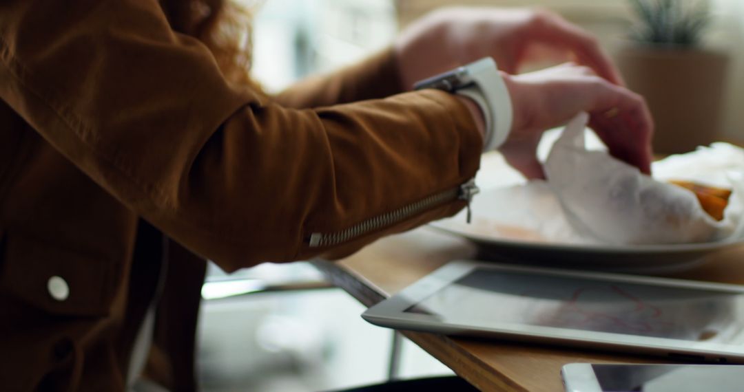 Close-Up of Person Wearing Smartwatch While Eating with Tablet on Table - Free Images, Stock Photos and Pictures on Pikwizard.com