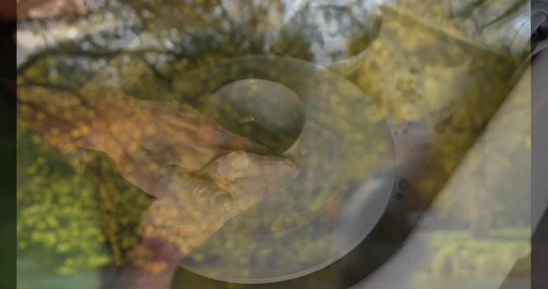 Artisan Shaping Wet Clay on Pottery Wheel with Window Reflection