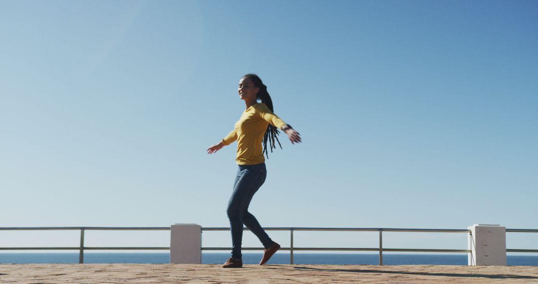 Joyful Woman Dancing Outdoors by Ocean on Sunny Day - Free Images, Stock Photos and Pictures on Pikwizard.com