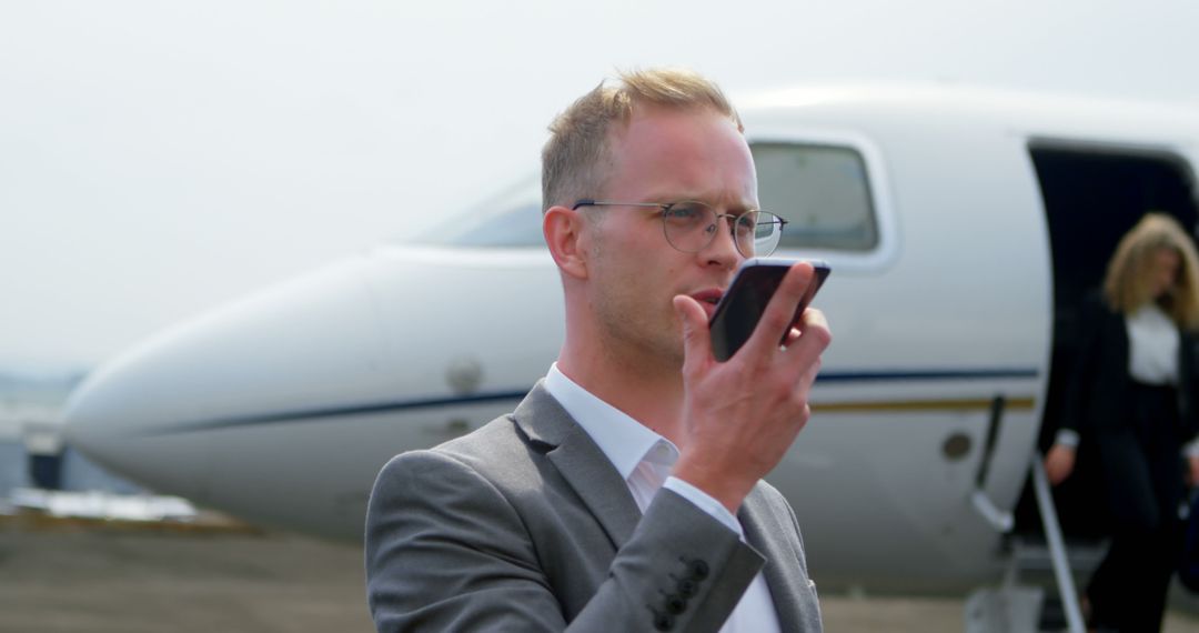 Businessman Communicating on Phone Near Private Jet at Airport
