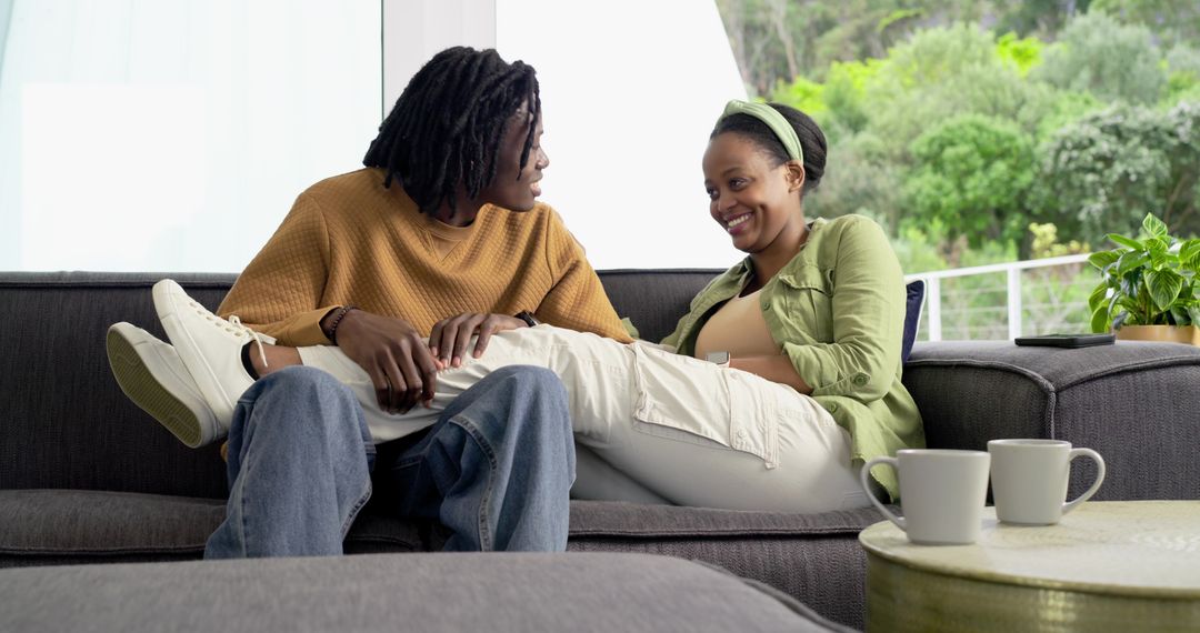 African American couple relaxing and smiling on sofa sharing intimate cozy moment at home