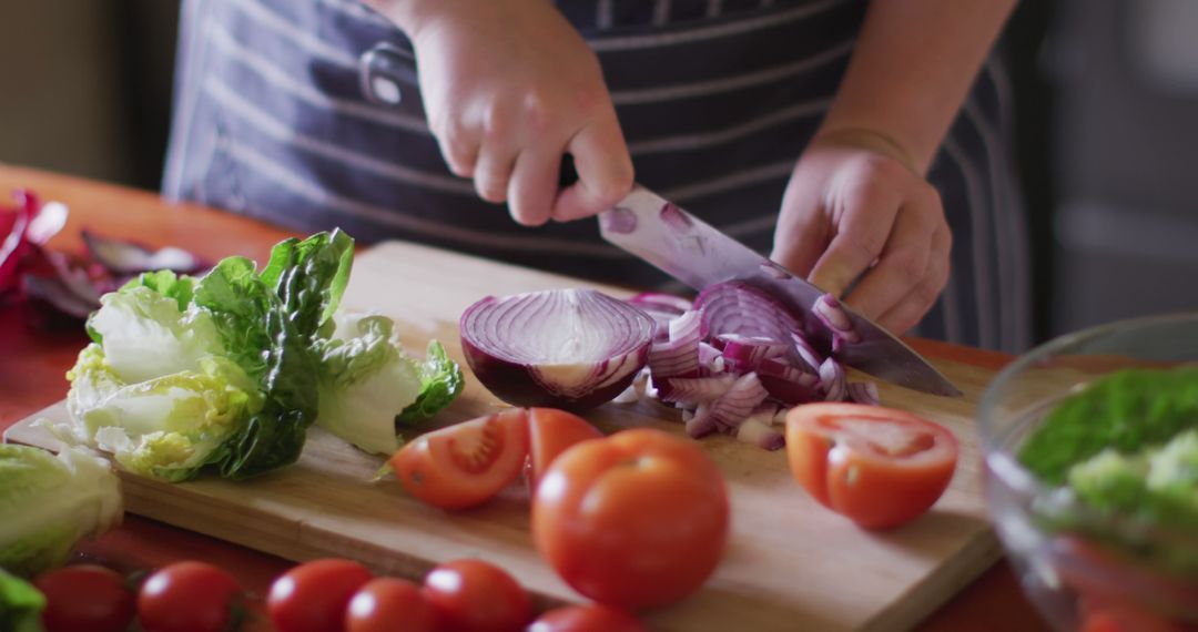 Person Slicing Red Onion in Kitchen Filled with Fresh Vegetables - Free Images, Stock Photos and Pictures on Pikwizard.com