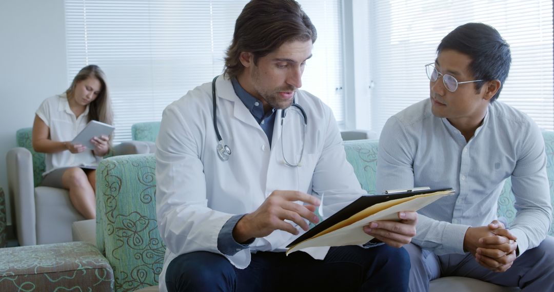 Doctor Discussing Medical Documents with Male Patient in Waiting Room - Free Images, Stock Photos and Pictures on Pikwizard.com