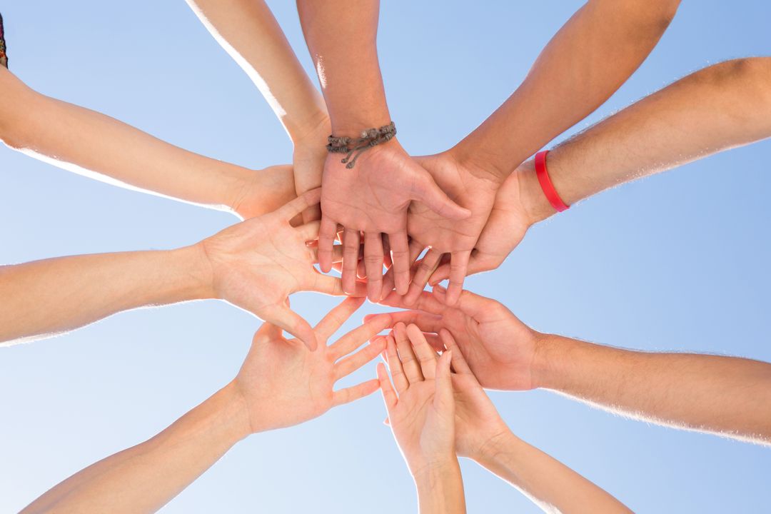 Friends Stacking Hands in Unity Against Clear Sky - Free Images, Stock Photos and Pictures on Pikwizard.com