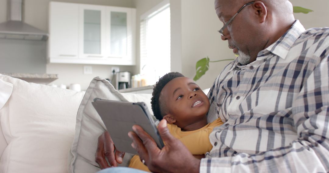 Grandfather Reading Tablet with Grandson on Couch - Free Images, Stock Photos and Pictures on Pikwizard.com