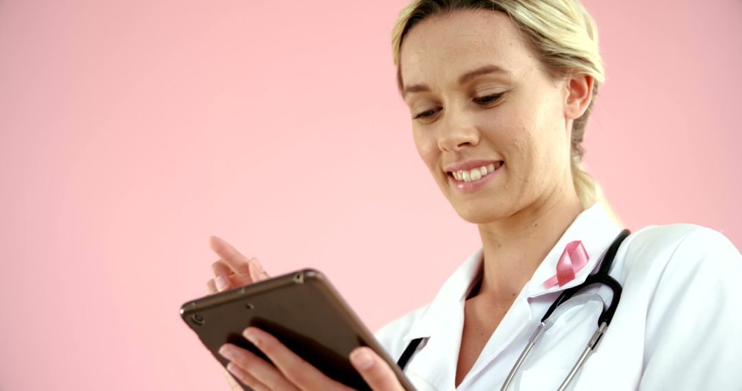 Smiling Female Doctor Using Tablet Against Pink Background - Free Images, Stock Photos and Pictures on Pikwizard.com