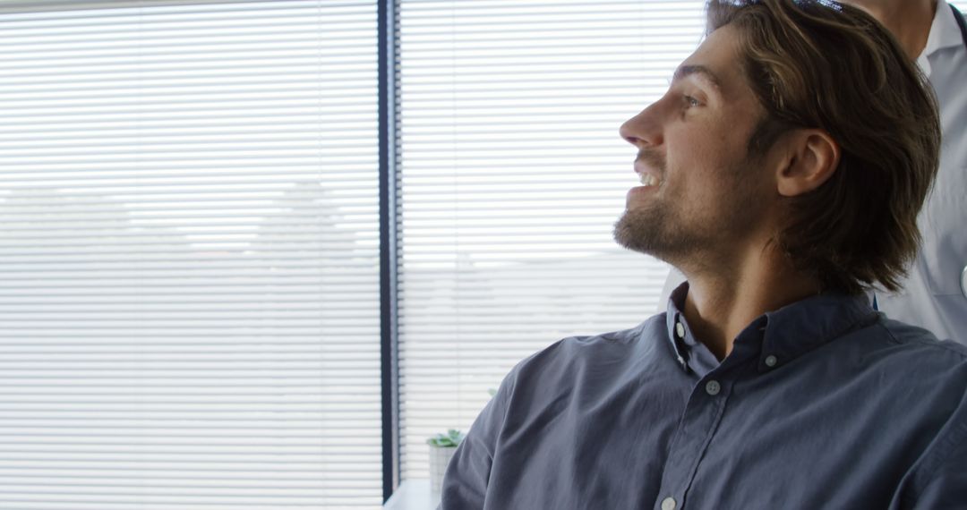 Smiling Young Man in Office Look Towards Colleague - Free Images, Stock Photos and Pictures on Pikwizard.com