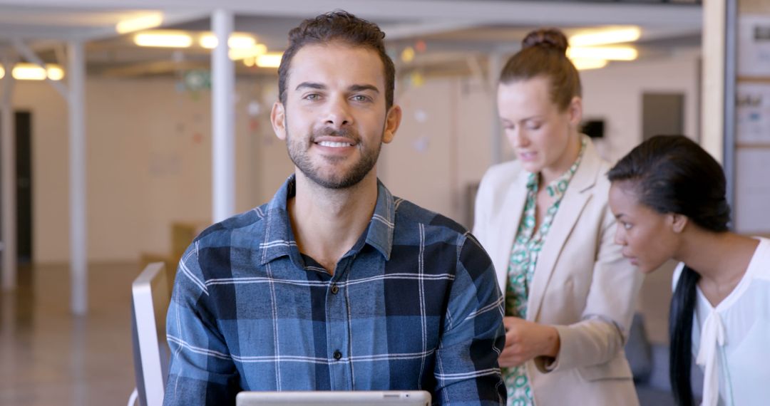 Smiling Professional in Modern Office with Female Colleagues