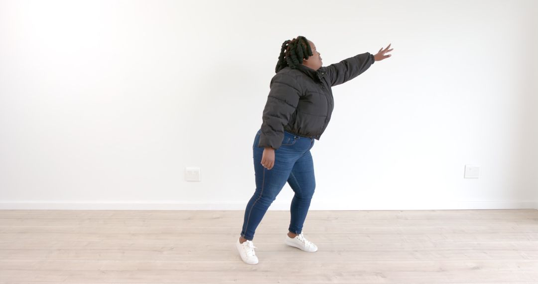 Woman in Denim and Puffer Jacket Reaching Out Energetically in Minimalist Room