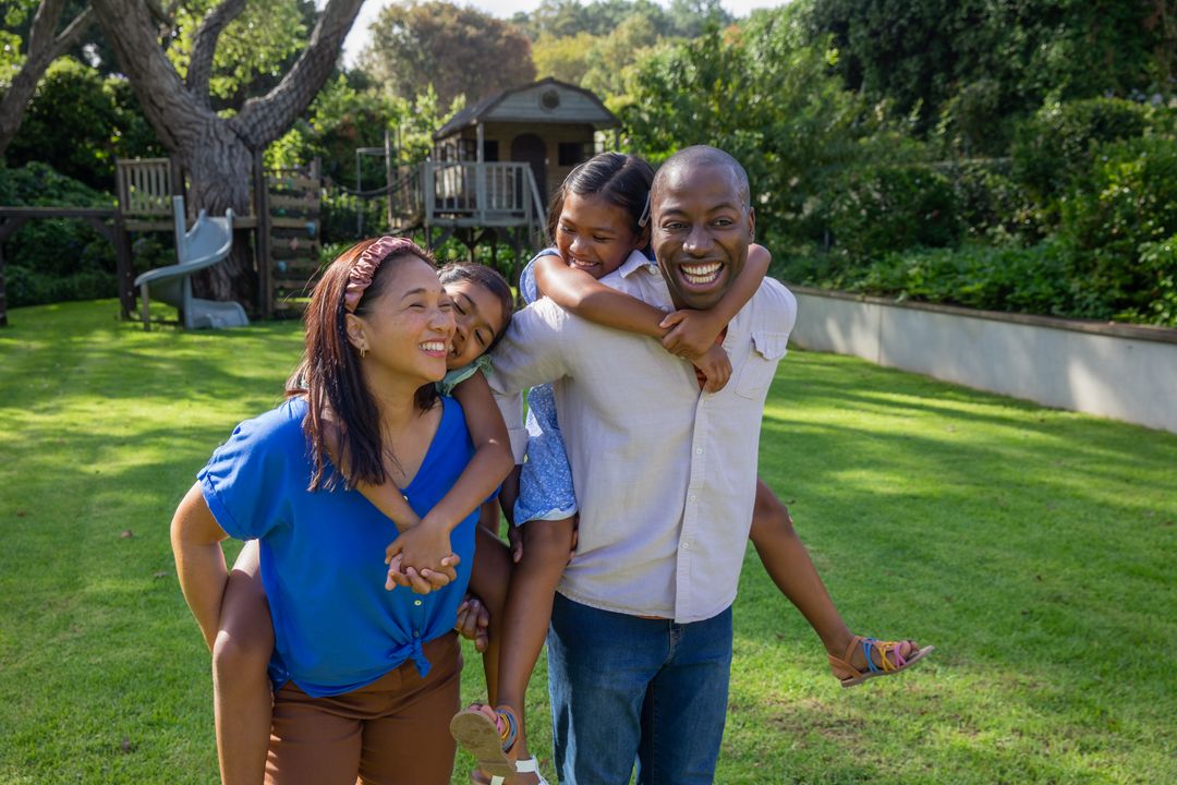 Happy Family Enjoying Piggyback Fun in Lush Backyard Playground