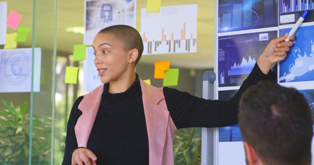 Businesswoman Presenting Data in Modern Office with Glass Walls and Sticky Notes - Free Images, Stock Photos and Pictures on Pikwizard.com