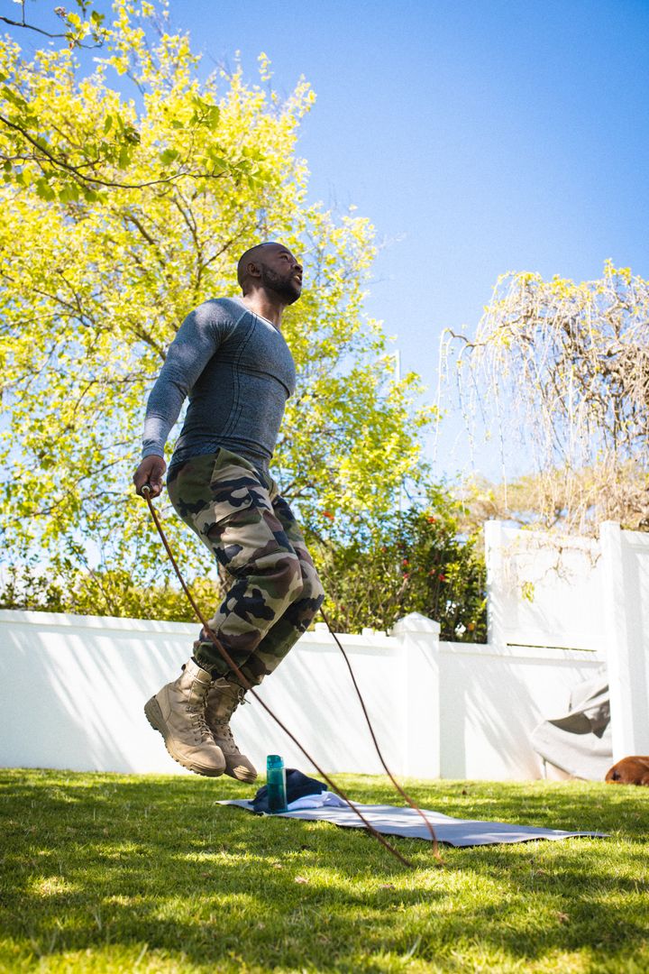 Happy african american man wearing military uniform exercising in backyard - Free Images, Stock Photos and Pictures on Pikwizard.com