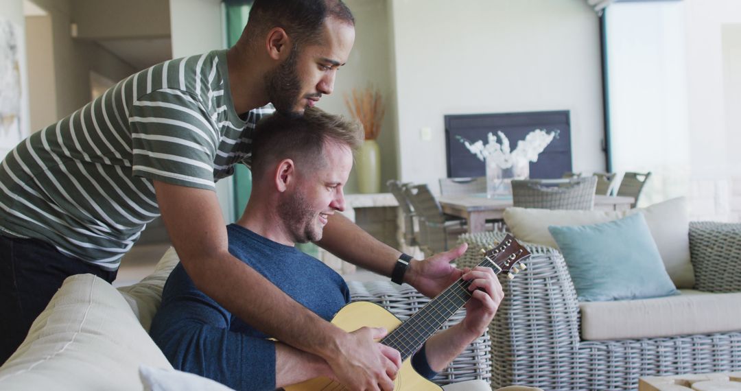 Two men bonding while playing guitar at home - Free Images, Stock Photos and Pictures on Pikwizard.com