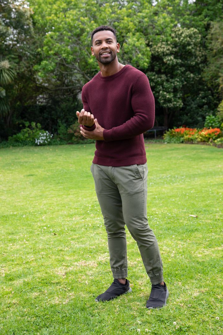 Man in Burgundy Sweater Relaxing in Lush Green Garden